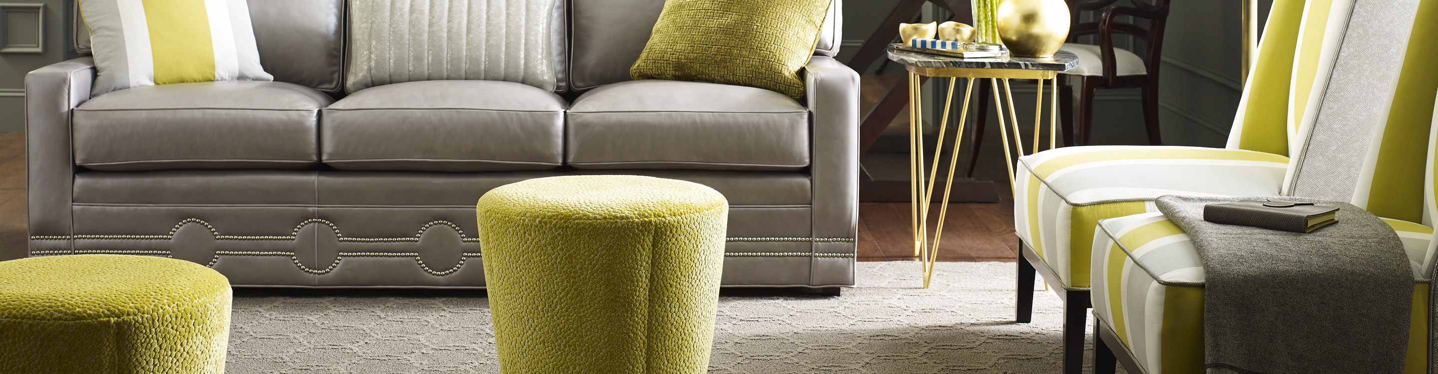 Neutral light brown patterned area rug in living area with gray and lime green armchairs and gray sofa